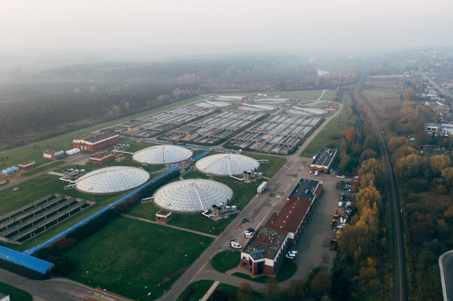 A large wastewater treatment works on a misty day. There is an urban area to the right of the image.